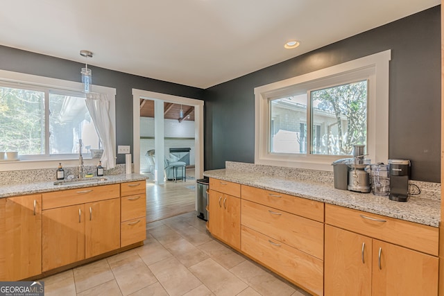 kitchen featuring light stone countertops, sink, hanging light fixtures, and plenty of natural light