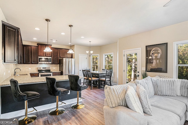 living room with sink, light hardwood / wood-style floors, and a notable chandelier