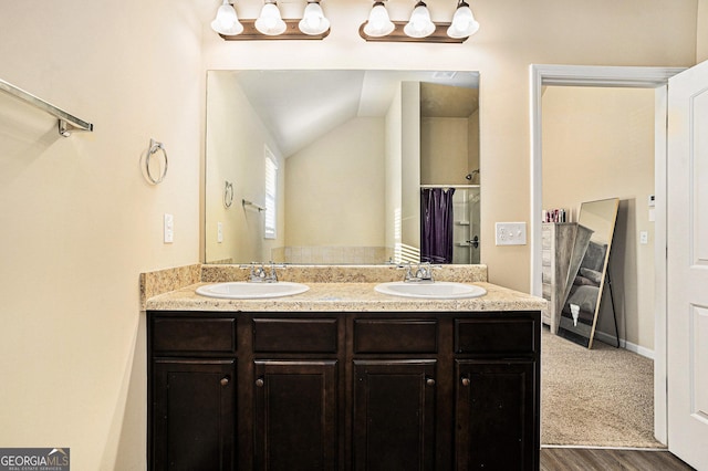 bathroom featuring hardwood / wood-style floors, vanity, lofted ceiling, and walk in shower