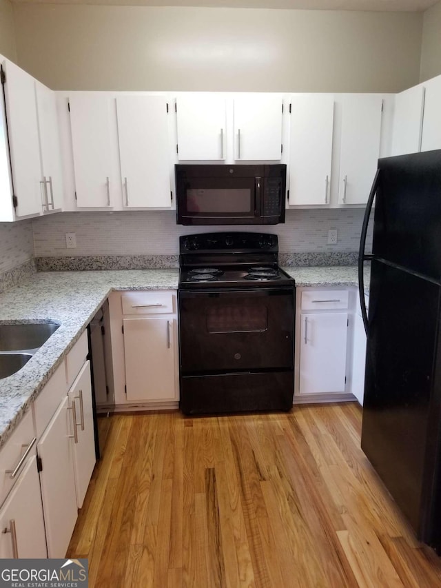 kitchen featuring light stone countertops, white cabinetry, light hardwood / wood-style flooring, backsplash, and black appliances