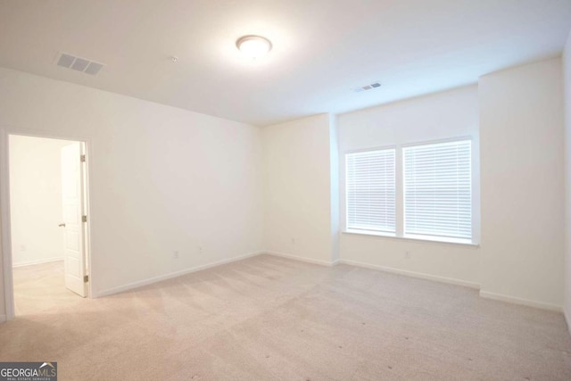 spare room featuring light carpet, baseboards, and visible vents