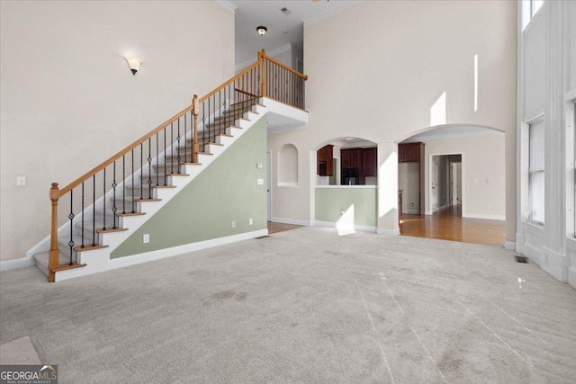 unfurnished living room featuring a towering ceiling and carpet flooring