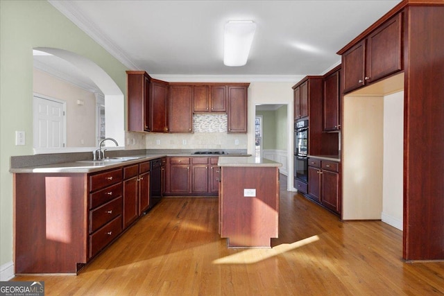 kitchen featuring sink, crown molding, a center island, decorative backsplash, and black appliances