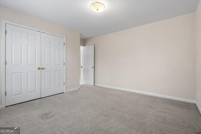 unfurnished bedroom featuring light colored carpet and a closet