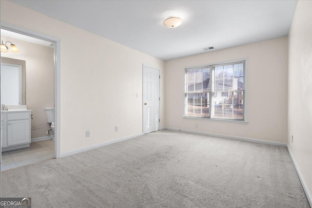 unfurnished bedroom with light colored carpet and ensuite bath