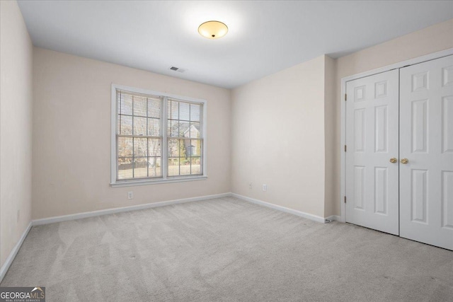 unfurnished bedroom with light carpet and a closet