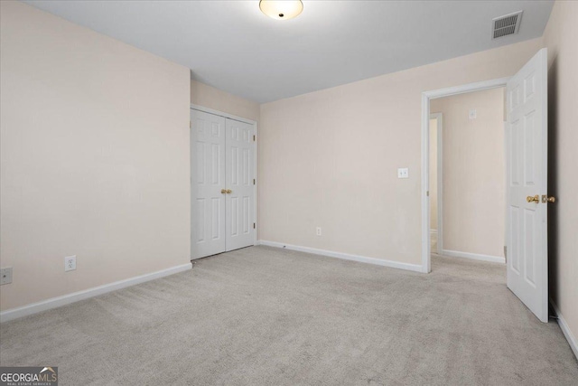 unfurnished bedroom with light colored carpet and a closet