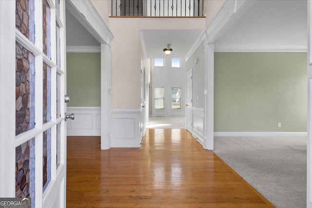 carpeted foyer with a towering ceiling and ornamental molding