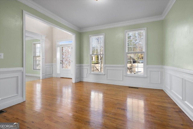 empty room with ornamental molding and wood-type flooring