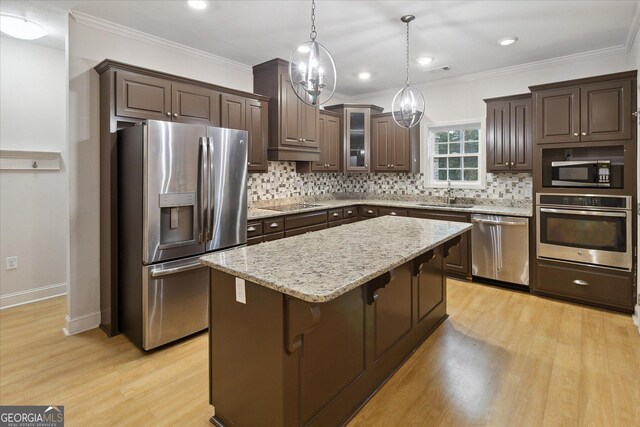 kitchen featuring pendant lighting, sink, a kitchen island, dark brown cabinetry, and stainless steel appliances