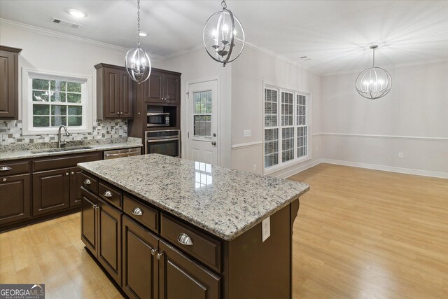 kitchen featuring pendant lighting, stainless steel oven, sink, a kitchen island, and dark brown cabinetry