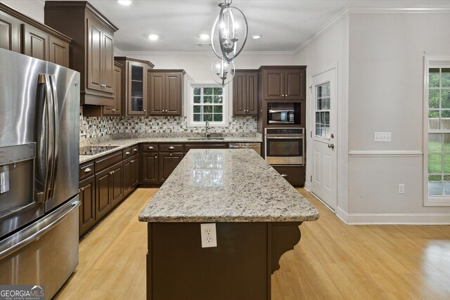 kitchen featuring sink, pendant lighting, dark brown cabinets, a kitchen island, and appliances with stainless steel finishes