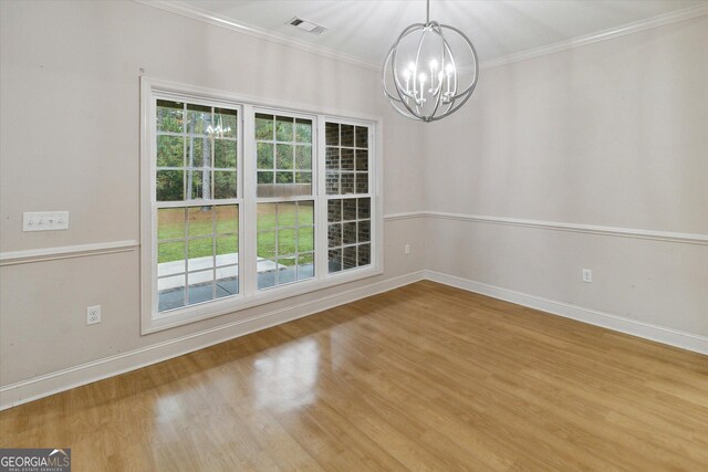 spare room with crown molding, wood-type flooring, and a notable chandelier