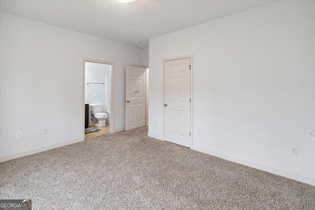 unfurnished bedroom featuring ensuite bath and carpet