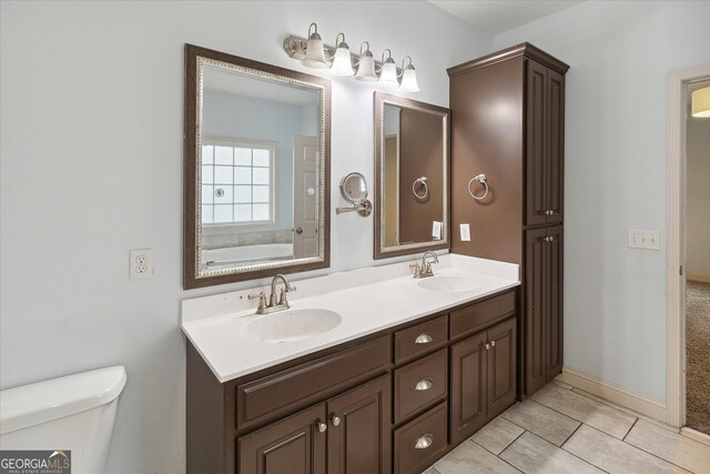 bathroom featuring tile patterned floors, vanity, toilet, and a tub to relax in