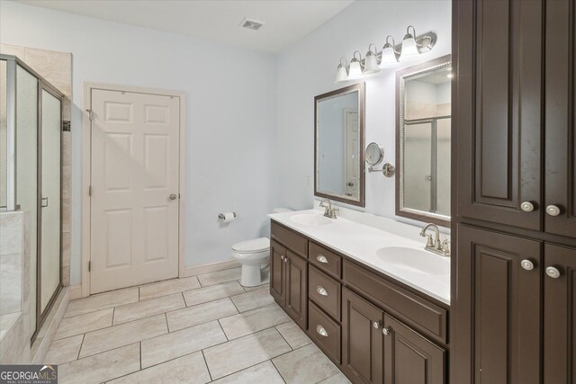 bathroom featuring tile patterned flooring, vanity, toilet, and walk in shower