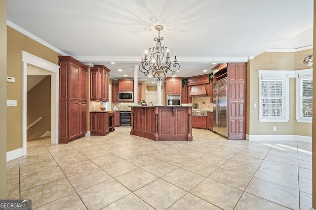 kitchen featuring an inviting chandelier, hanging light fixtures, built in appliances, tasteful backsplash, and a kitchen island