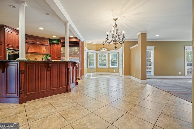 kitchen with an inviting chandelier, crown molding, hanging light fixtures, dark stone countertops, and light tile patterned floors