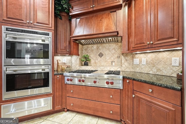 kitchen featuring light tile patterned flooring, dark stone counters, custom range hood, and appliances with stainless steel finishes