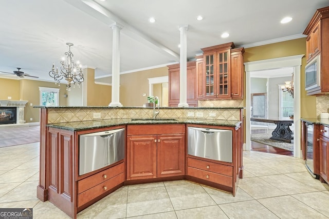 kitchen featuring backsplash, dark stone counters, crown molding, sink, and stainless steel appliances