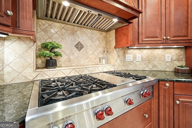 kitchen featuring decorative backsplash, custom range hood, stainless steel gas cooktop, and dark stone countertops