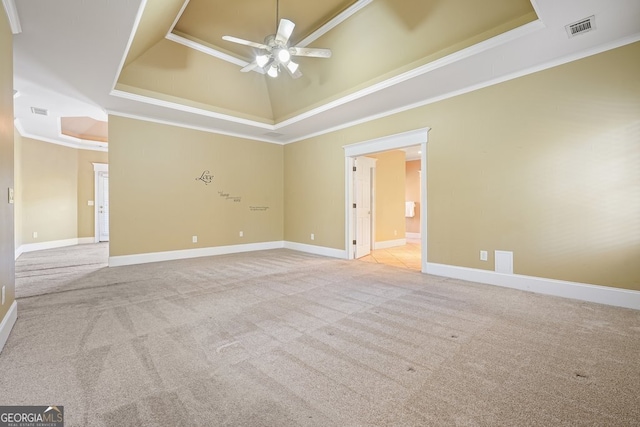 carpeted empty room with ceiling fan, crown molding, and a tray ceiling