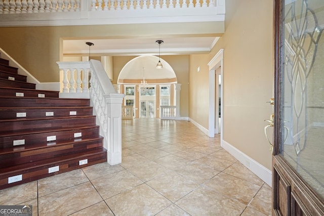 tiled foyer entrance featuring an inviting chandelier and ornamental molding