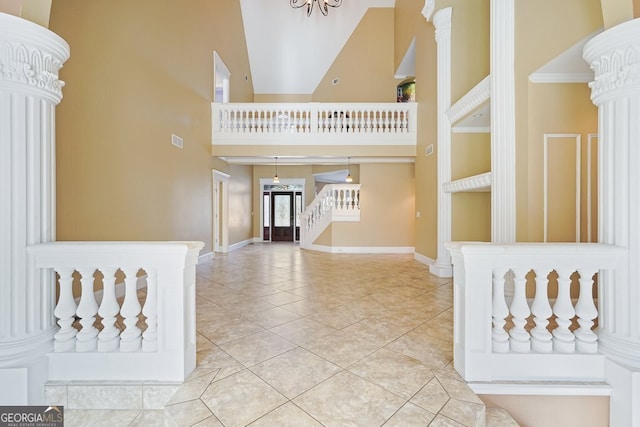 foyer entrance featuring tile patterned floors, high vaulted ceiling, and decorative columns