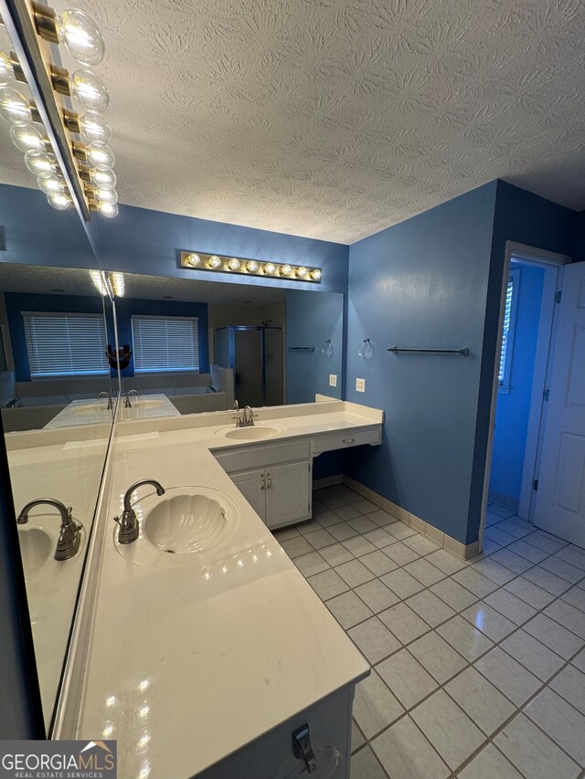 bathroom with tile patterned flooring, vanity, a shower with shower door, and a textured ceiling