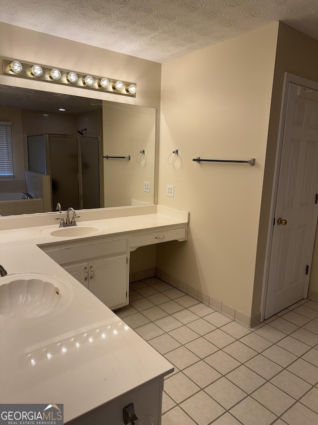 bathroom with tile patterned flooring, shower with separate bathtub, vanity, and a textured ceiling