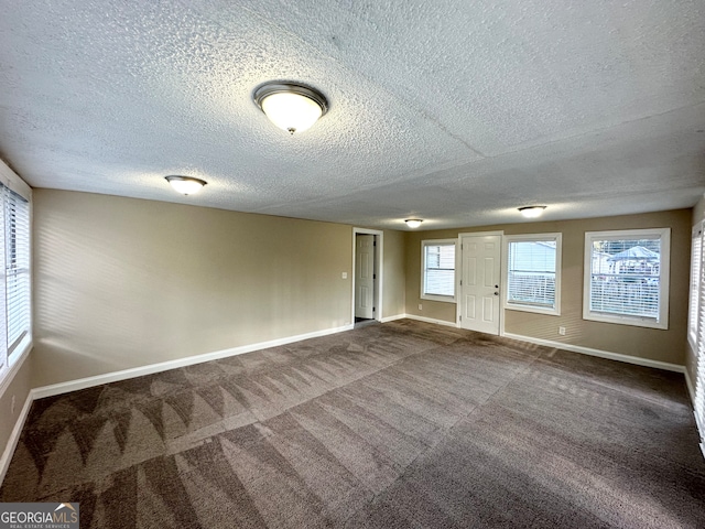 carpeted empty room featuring a textured ceiling