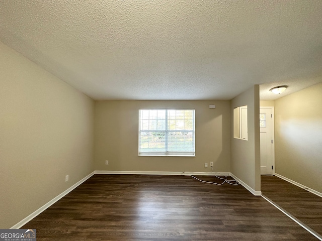 spare room with dark hardwood / wood-style floors and a textured ceiling