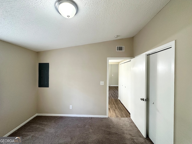 carpeted spare room with a textured ceiling, electric panel, and lofted ceiling