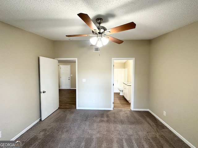 unfurnished bedroom with ceiling fan, dark carpet, a textured ceiling, and connected bathroom