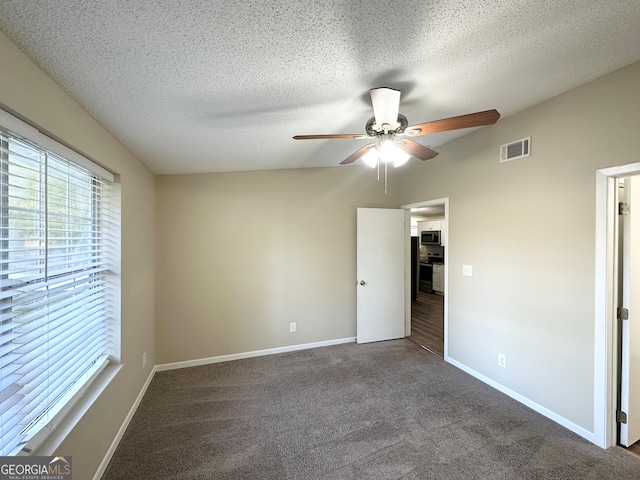 unfurnished bedroom with ceiling fan, dark carpet, and a textured ceiling