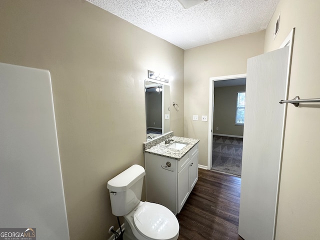 bathroom with toilet, vanity, a textured ceiling, and hardwood / wood-style flooring