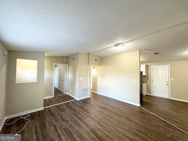 empty room with a textured ceiling and dark wood-type flooring