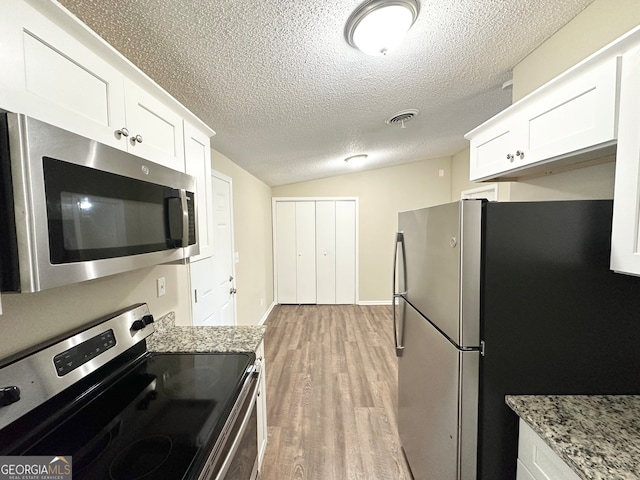 kitchen featuring light stone countertops, white cabinetry, stainless steel appliances, and light hardwood / wood-style floors