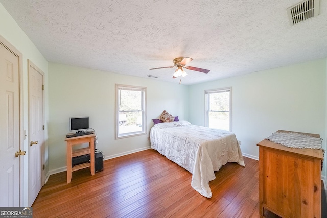 bedroom featuring dark hardwood / wood-style flooring, a textured ceiling, and ceiling fan