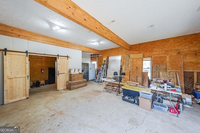 miscellaneous room with beam ceiling, a barn door, and concrete flooring