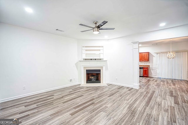 unfurnished living room with ceiling fan with notable chandelier and light hardwood / wood-style floors