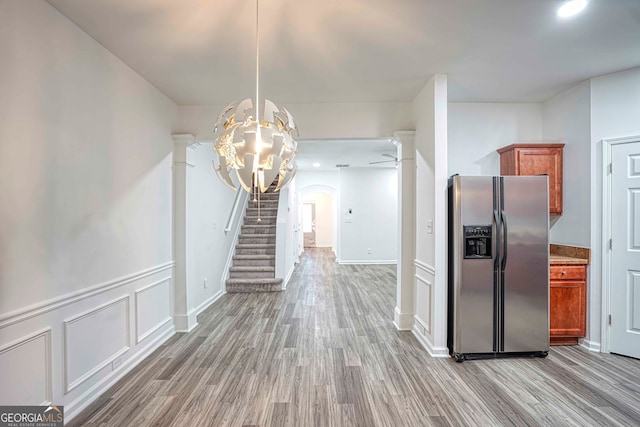 kitchen featuring stainless steel fridge, hardwood / wood-style floors, hanging light fixtures, and ceiling fan with notable chandelier