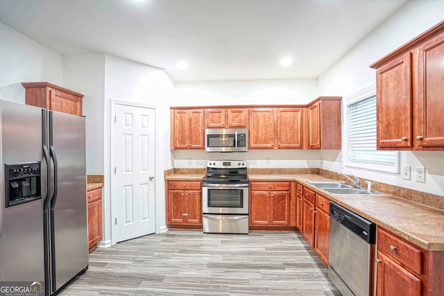 kitchen with appliances with stainless steel finishes, light hardwood / wood-style flooring, and sink