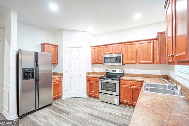 kitchen with sink, stainless steel appliances, and light hardwood / wood-style floors