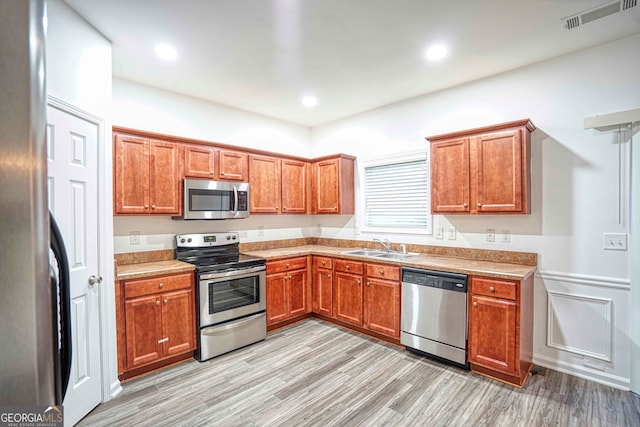 kitchen featuring stainless steel appliances, light hardwood / wood-style flooring, and sink