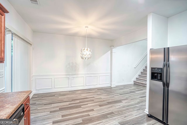 kitchen featuring a chandelier, stainless steel appliances, hanging light fixtures, and light hardwood / wood-style floors