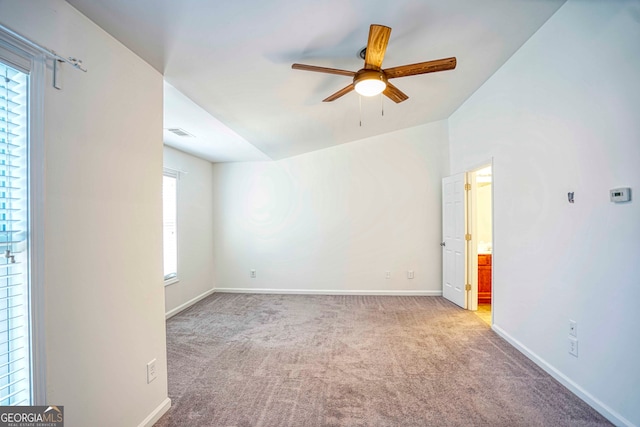 spare room featuring light carpet, vaulted ceiling, and ceiling fan