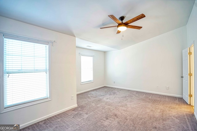 empty room featuring a wealth of natural light, ceiling fan, and light colored carpet