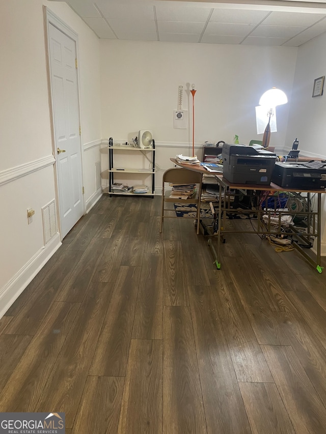 interior space with a paneled ceiling and dark wood-type flooring