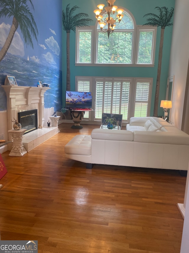 living room with a tiled fireplace, a healthy amount of sunlight, a high ceiling, and hardwood / wood-style flooring